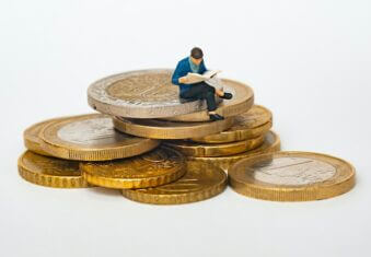 Small man sat on large pound coins