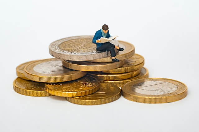 Small man sat on large pound coins